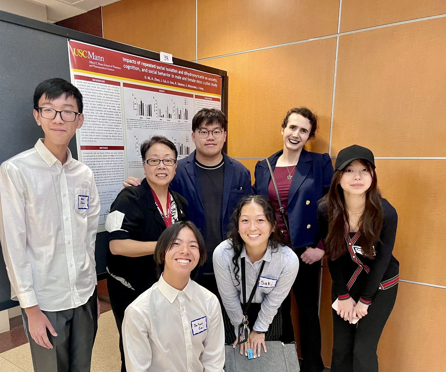 The lab group gathered in front of the poster, name badges on