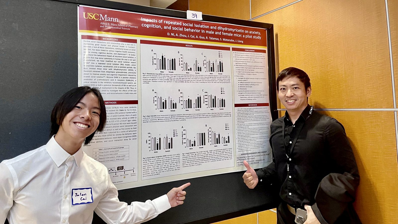 Jalen and a labmate pointing at the poster on repeated social isolation and dihydromyricetin, both smiling