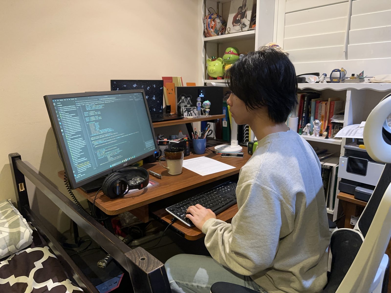 Jalen at a desk working through the analysis code on a monitor, headphones and a notebook beside the keyboard
