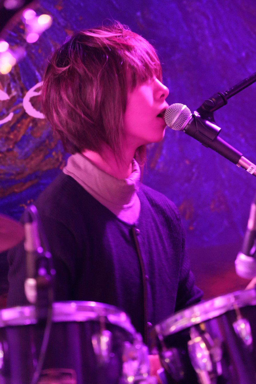 Jalen singing into a microphone from behind the drums, lit purple against the Starry Night backdrop