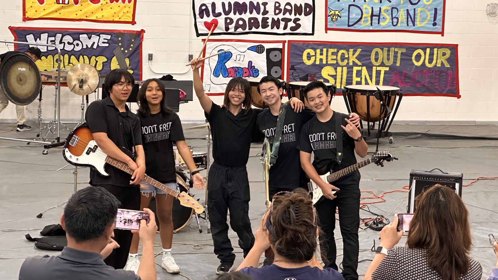The band in matching black Don't Fret T-shirts posing with their instruments in front of hand-painted banners, a gong and timpani behind them