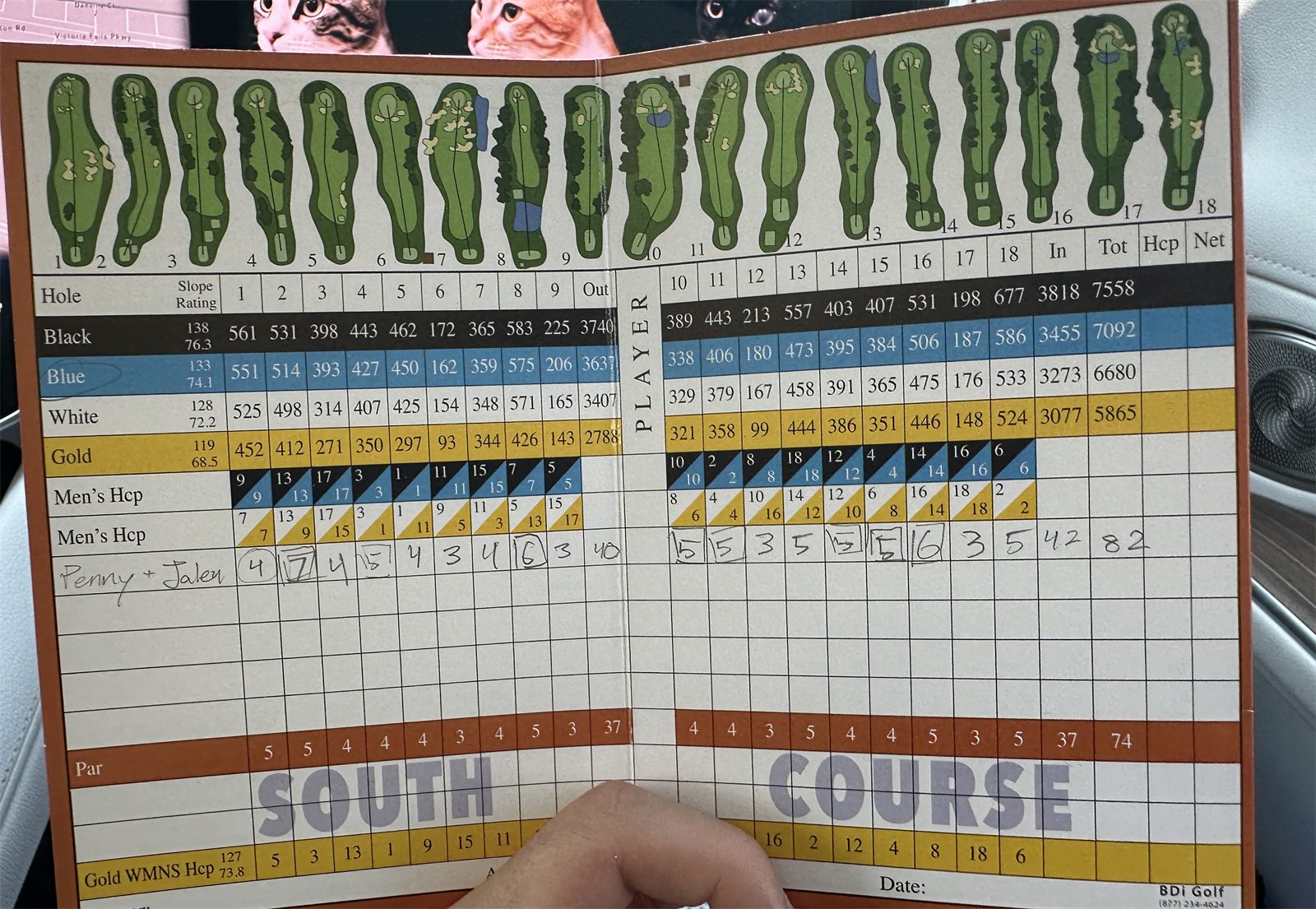 A hand holding a South Course golf scorecard in a car, the player line reading Penny + Jalen with a total of 82